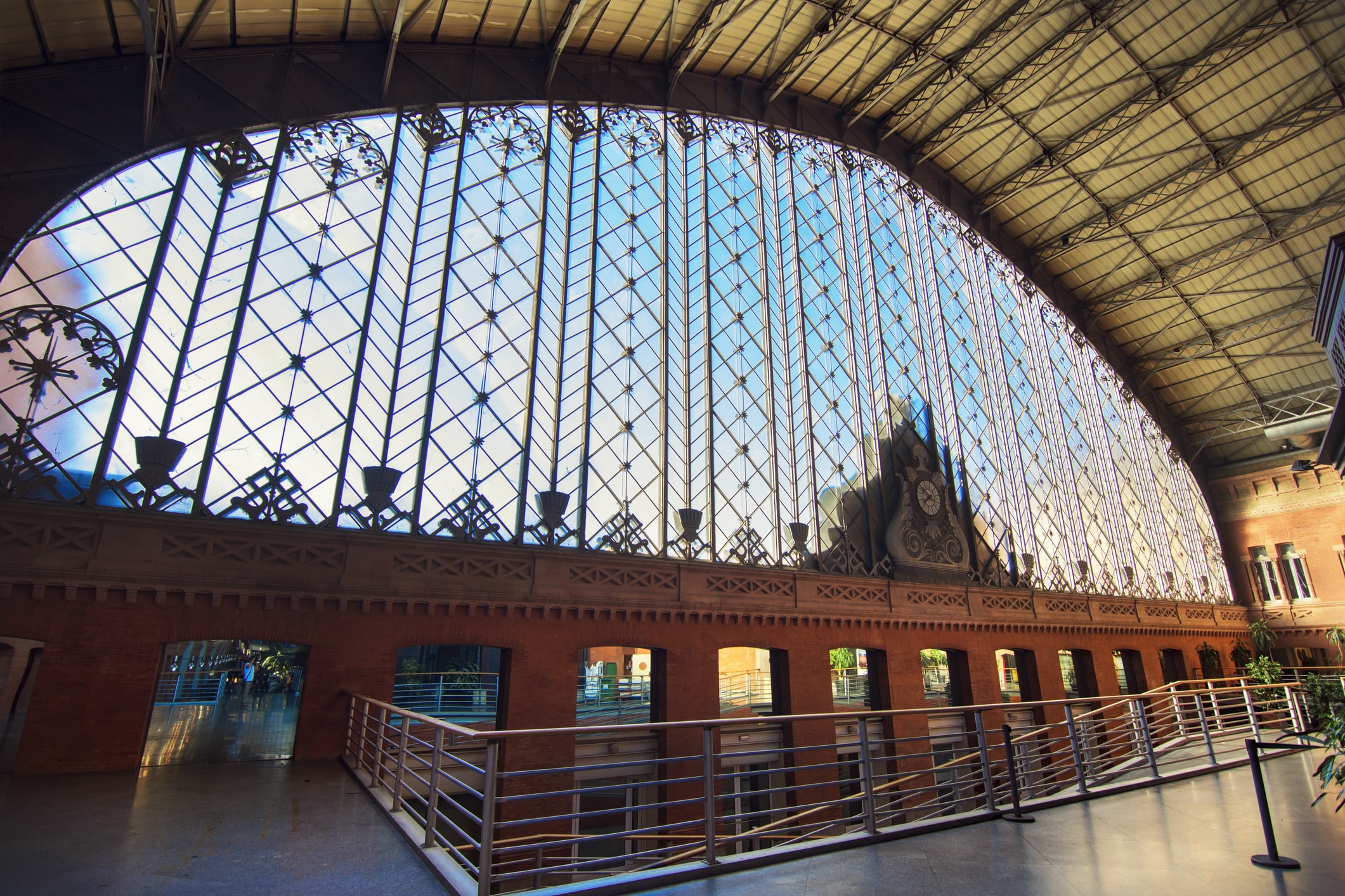 Looking our the large glass and wrought iron window at the front of Atocha train station in Madrid.