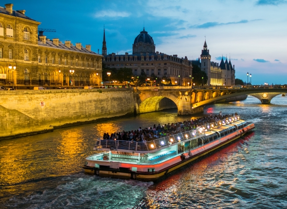 Bateau Mouche cruising on Seine river at sunset, Paris.