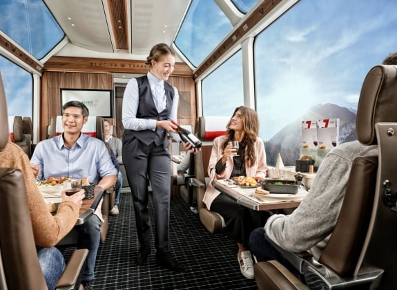 Glacier Express - Excellence Class Train staff serve onboard customers with drinks in luxurious carriage