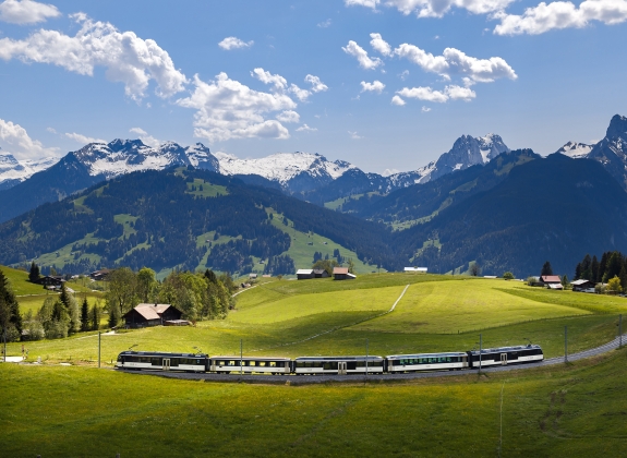 The GoldenPass route A train travels through a valley with high mountains in the background
