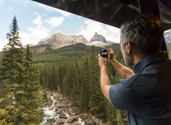 man taking picture of mountains from Rocky Mountaineer platform
