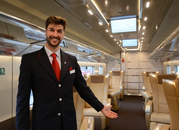 Train staff welcome you onboard a First Class Carriage