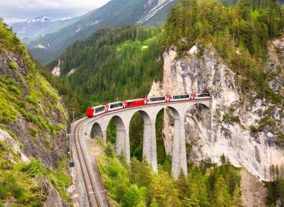 Swiss red train on viaduct in mountain, scenic ride