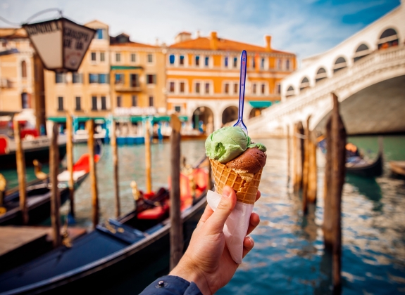 Hand man holds an Italian ice cream on background of Grand Canal and Handol in Venice, Italy. Concept tourism.