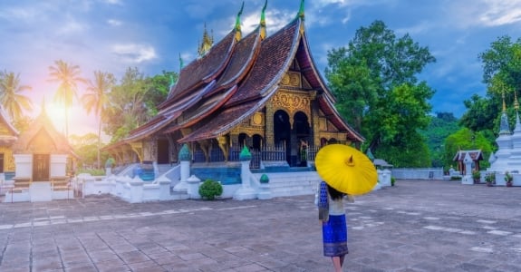 Asian woman wearing a Lao national costume visits Wat Xieng Thong in Luang Prabang, Laos