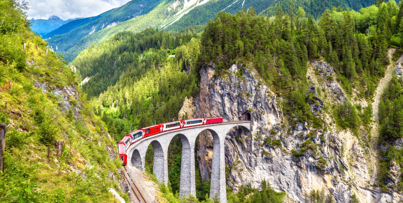 Glacier express on Landwasser Viaduct, Switzerland. It is landmark of Swiss Alps. Red Bernina train runs on railroad bridge in mountains.