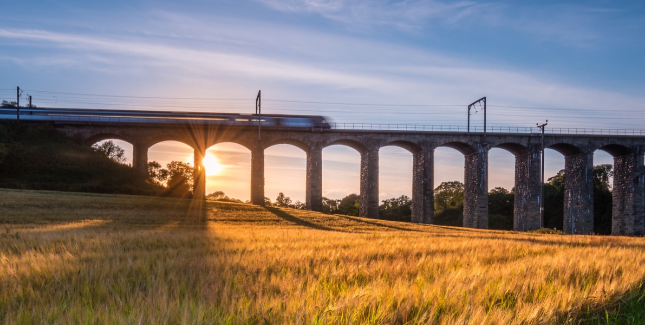 UK Train Travel A train crossing a viaduct at sunset