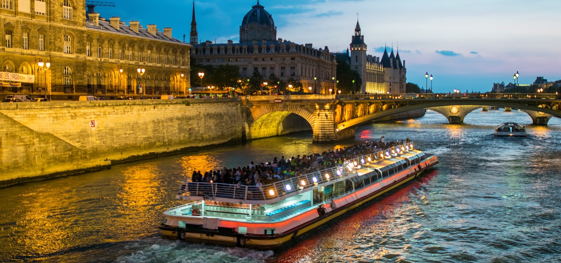Bateau Mouche cruising on Seine river at sunset, Paris.