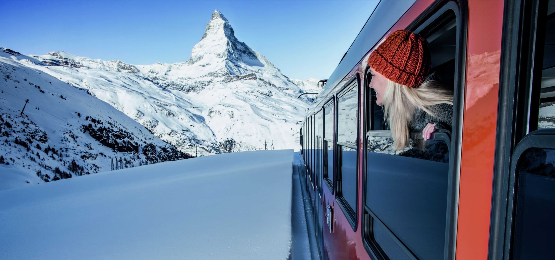 A train travels through snowy landscape towards Matterhorn