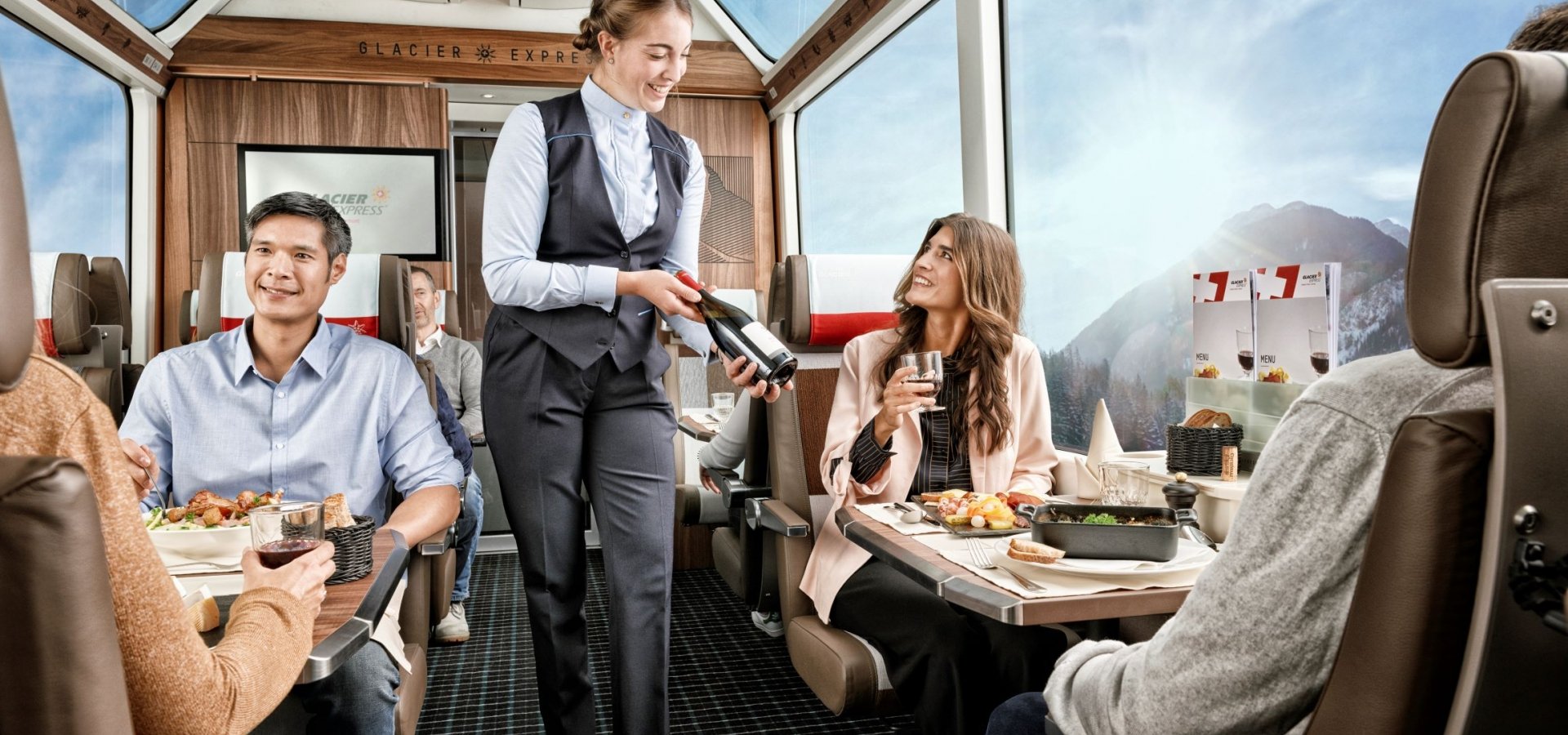 Train staff serve onboard customers with drinks in luxurious carriage
