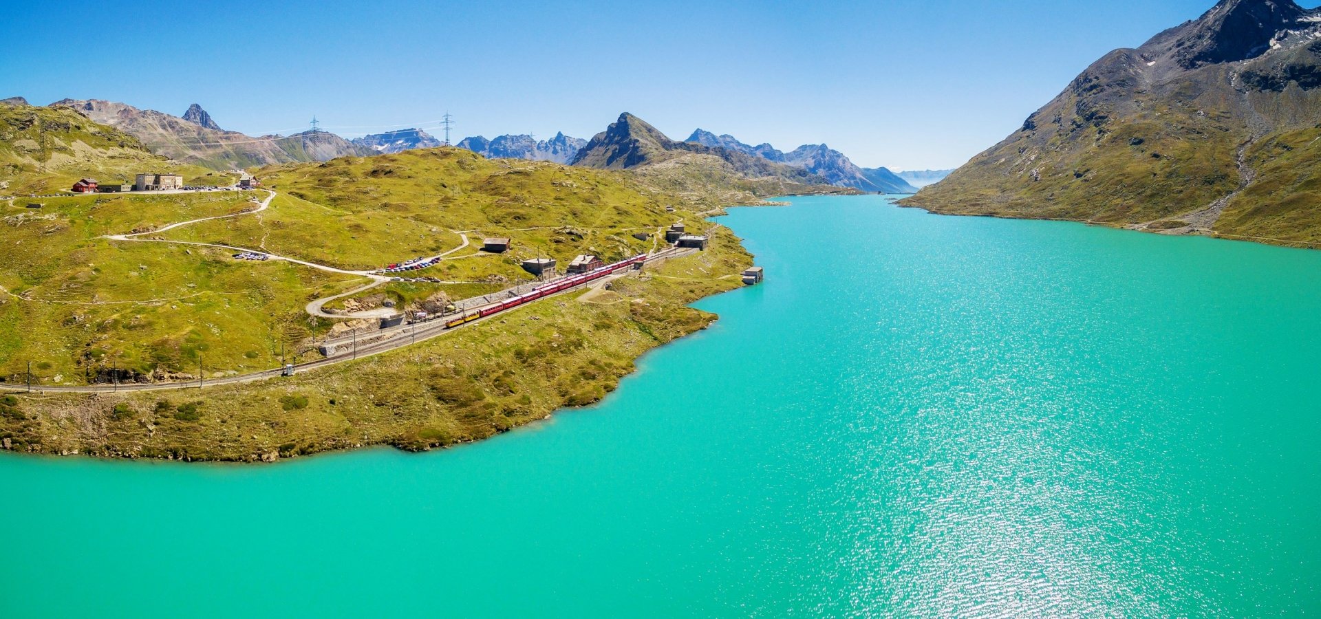 A train travels alongside a vast turquoise lake