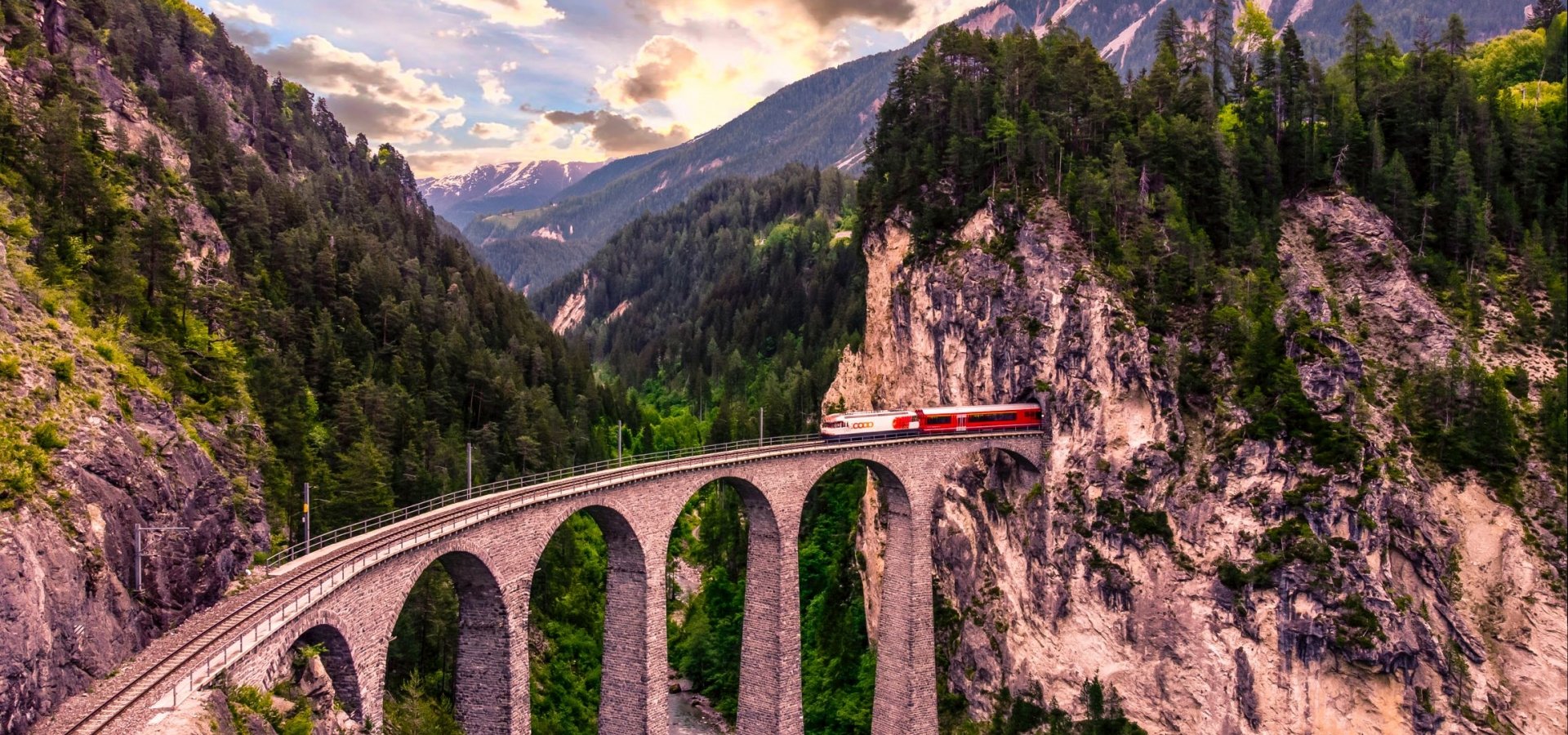 A train emerges from a tunnel crossing a viaduct