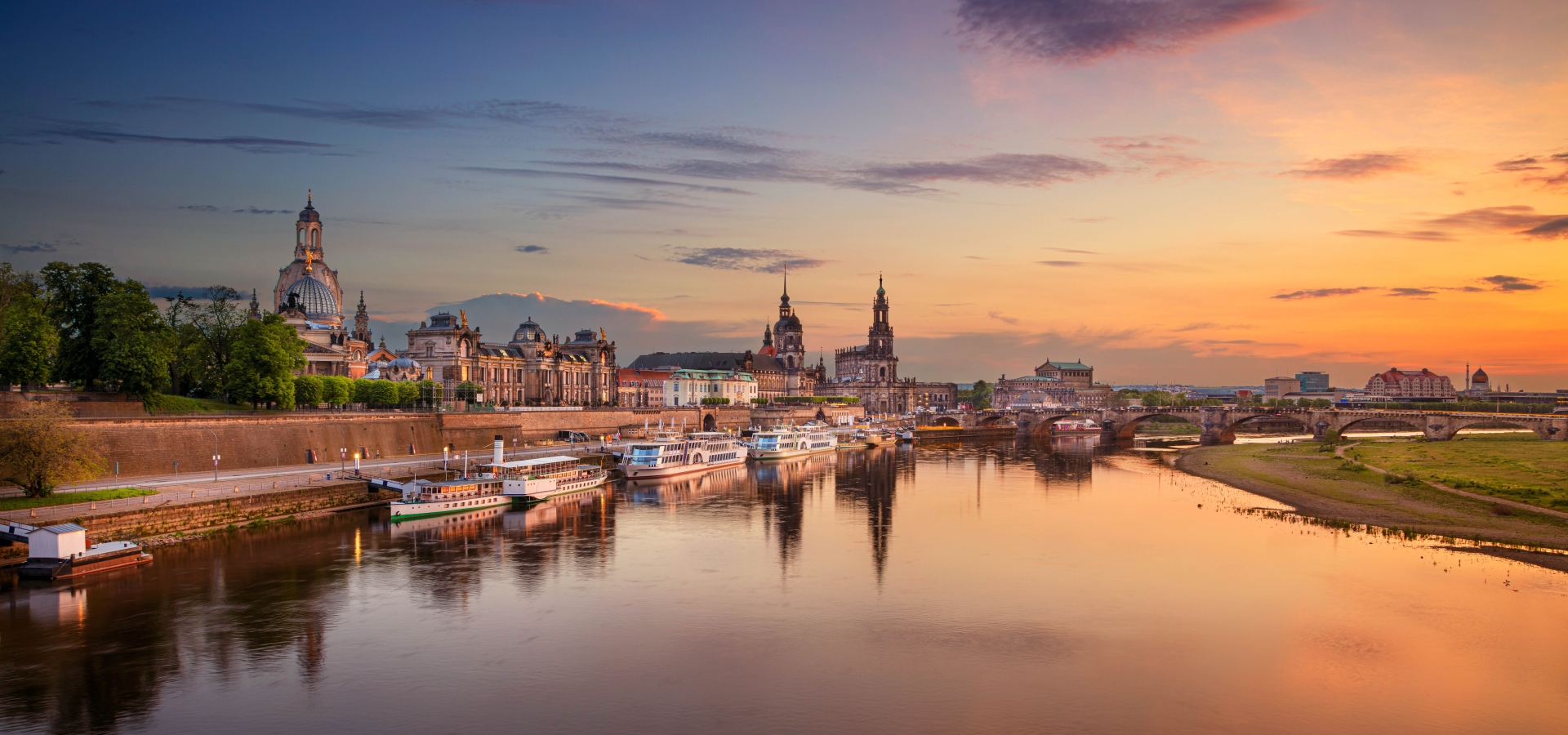 Panoramic cityscape image of Dresden, Germany with reflection of the city in the Elbe river, during sunset.