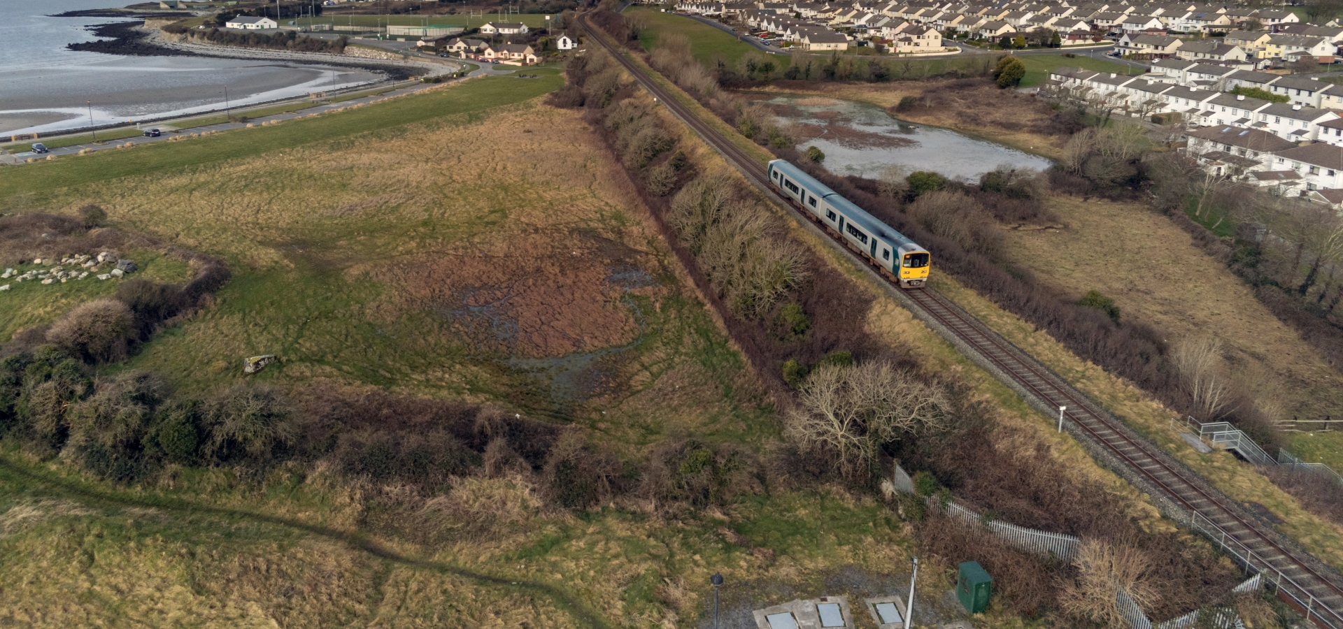 A train travels across flat coastal landscape