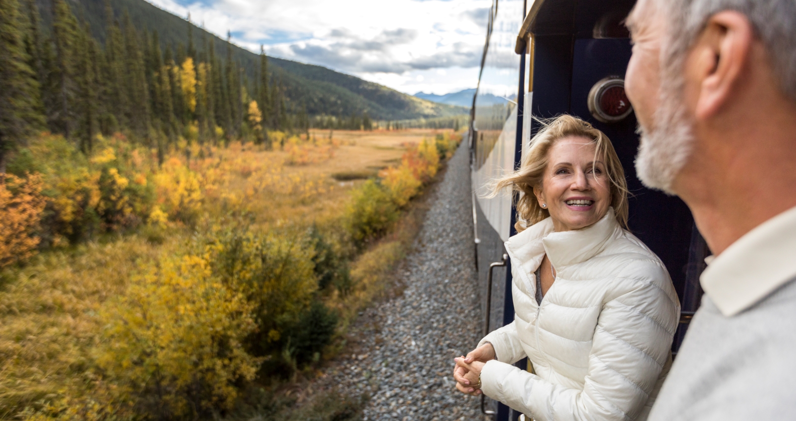 happy couple on platform of Rocky Mountaineer during train holiday