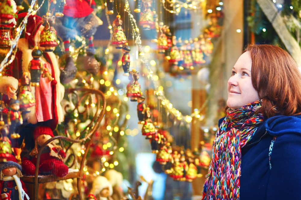 Young girl looking at shop-windows decorated for Christmas